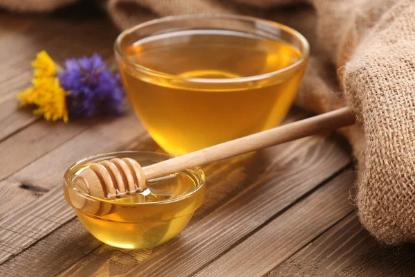 Honey in a glass bowl on a wooden boards background — Stock Photo, Image