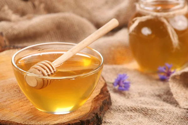 Honey in a glass bowl on a wooden boards background — Stock Photo, Image