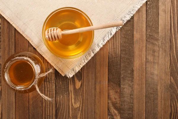 Honey in a glass bowl on a wooden boards background — Stock Photo, Image