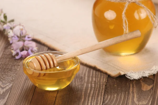 Honey in a glass bowl on a wooden boards background — Stock Photo, Image