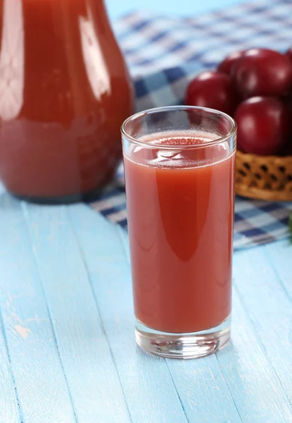 Plommon juice i ett glas och kannan, plommon i en flätad korg — Stockfoto