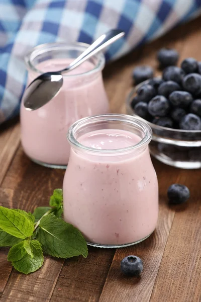 Yogurt con mirtilli in un barattolo di vetro e mirtilli in una ciambella — Foto Stock