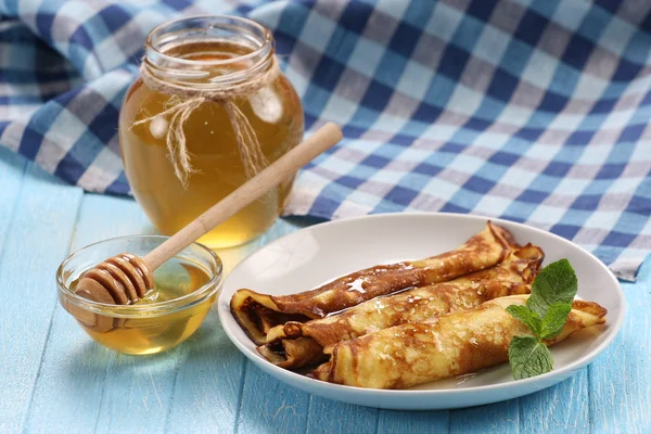 Pfannkuchen mit Honig auf einem Teller, der Honig in einer Glasschüssel — Stockfoto