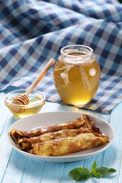 Pfannkuchen mit Honig auf einem Teller, der Honig in einer Glasschüssel — Stockfoto