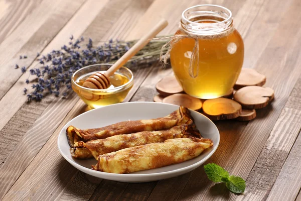 Pfannkuchen mit Honig auf einem Teller, den Honig in einer Glasschüssel auf einem l — Stockfoto