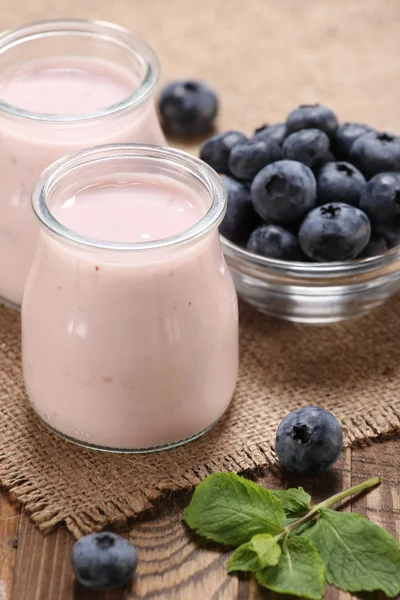 Yogurt con mirtilli in un barattolo di vetro e mirtilli in una ciambella — Foto Stock