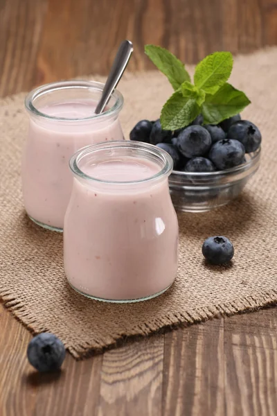 Yogurt with blueberries in a glass jar and blueberries in a glas — Stock Photo, Image