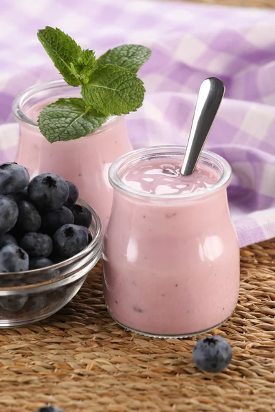 Yaban mersini bir glas içinde ve yaban mersini bir cam kavanoza yoğurt — Stok fotoğraf