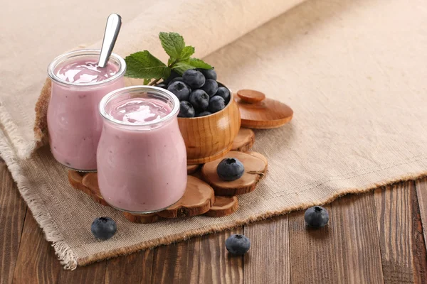 Yoghurt med blåbær i glasskrukke og blåbær i tre – stockfoto