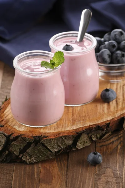 Yogurt with blueberries in a glass jar and blueberries in a glas — Stock Photo, Image