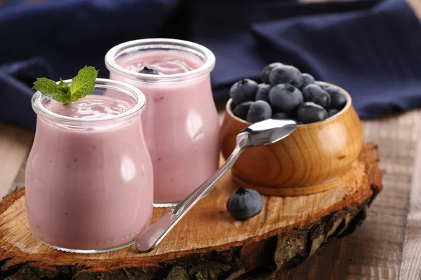 Yogurt with blueberries in a glass jar and blueberries in a wood — Stock Photo, Image