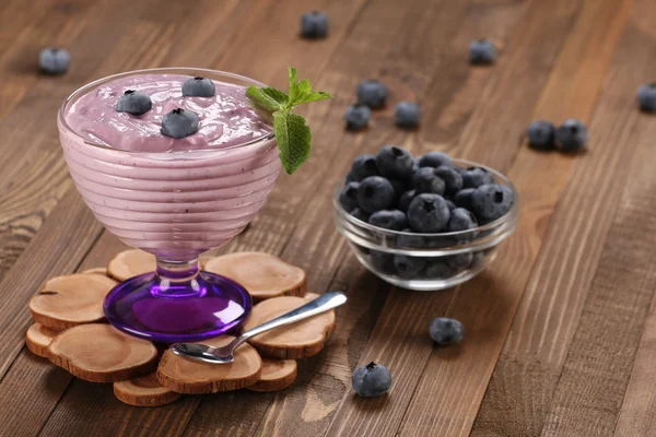 Yogurt con mirtilli in una ciotola di vetro e mirtilli in una gla — Foto Stock