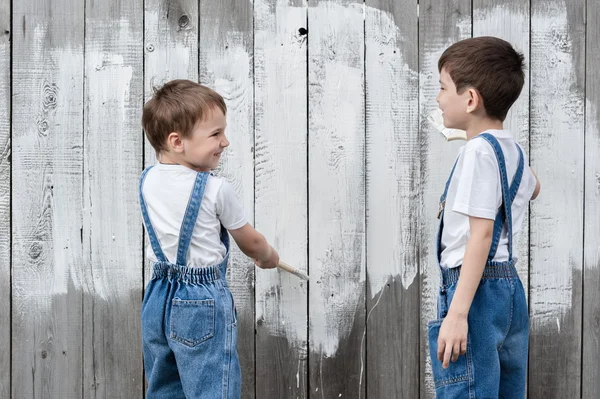 Мальчики с кисточками и краской у старой стены — стоковое фото