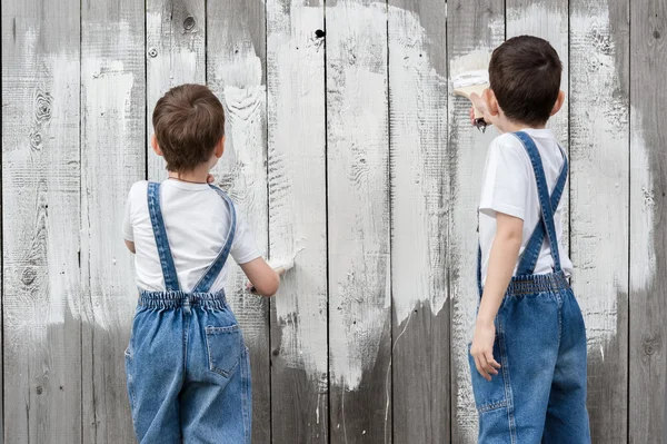 Мальчики с кисточками и краской у старой стены — стоковое фото