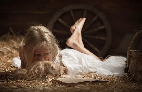 Mädchen mit einem Kätzchen auf Heu — Stockfoto