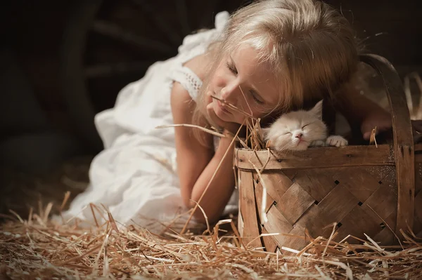 Девушка с котенком на сене — стоковое фото