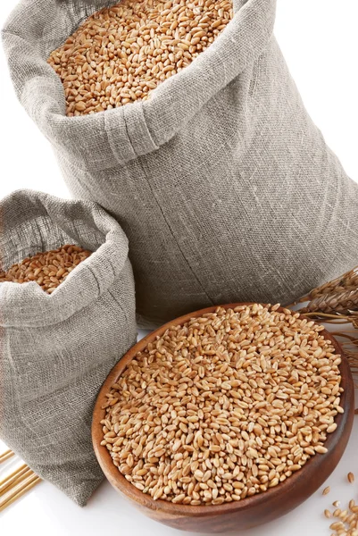 Grano del trigo en bolsas y un tazón — Foto de Stock