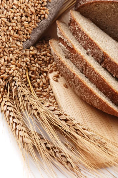 Pane tagliato su un'asse e un sacchetto con grano — Foto Stock
