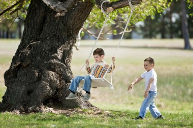 Children on a swing on a nature clipart