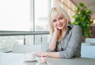 hermosa chica detrás de una taza de café en café