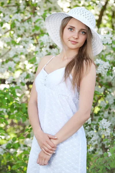 Meisje in een hoed onder bloeiende bomen — Stockfoto
