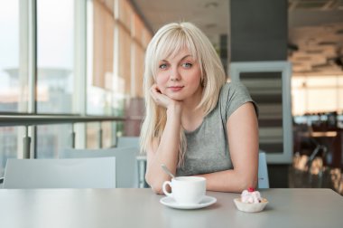 hermosa chica detrás de una taza de café en café