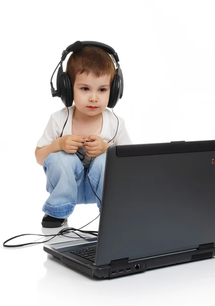 Kind in hoofdtelefoons en met computer — Stockfoto