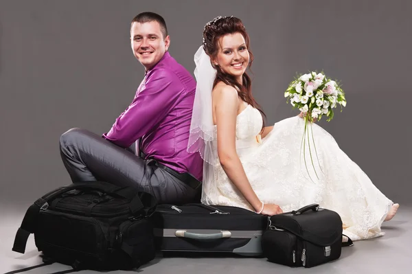 Bride and the groom sitting on a suitcase — Stock Photo, Image