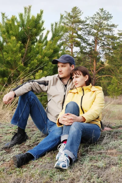 De jongen en het meisje zit op een gras — Stockfoto