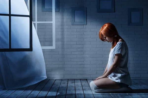 Самотня дівчина сидить у порожній темній кімнаті — стокове фото