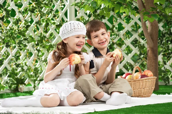 Menino e menina comendo maçã no jardim — Fotografia de Stock