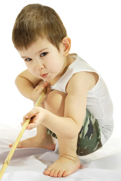 Malý chlapec sedí s bambusovou holí — Stock fotografie