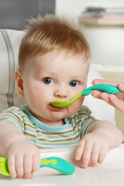 Mum feeds the little boy from a spoon — Stock Photo, Image