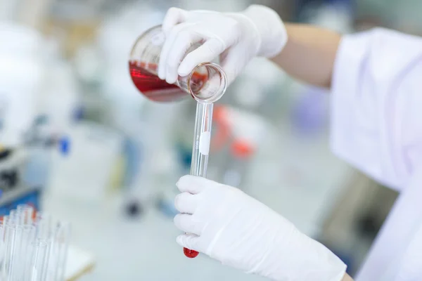 Decanting a violet liquid into a graduated cylinder — Stock Photo, Image