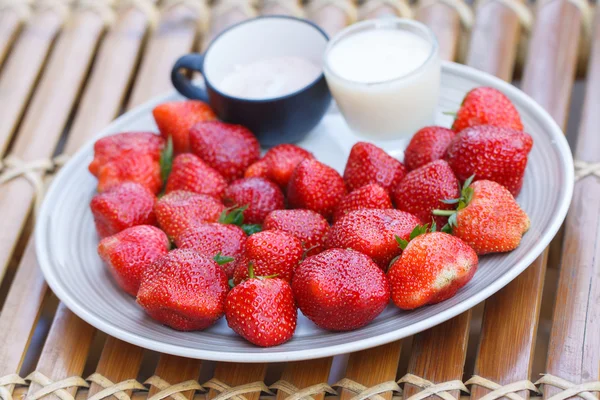 Strawberry in a cup of milk on bamboo table — Stock Photo, Image