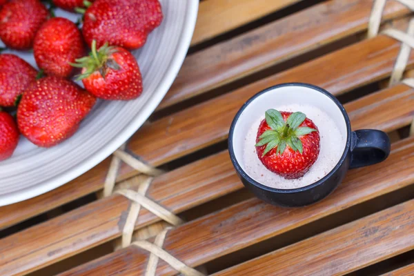 Strawberry in a cup of milk on bamboo table — Stock Photo, Image