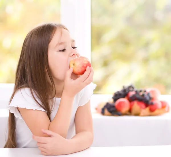 Küçük kız elma yiyor. Stok Fotoğraf