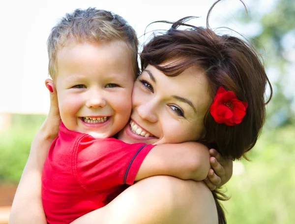 Rapaz bonito está brincando com sua mãe ao ar livre — Fotografia de Stock