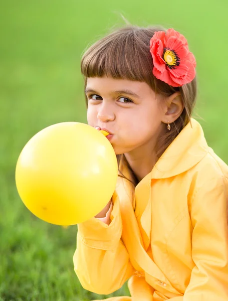 Little girl is inflating yellow balloon — Stock Photo, Image