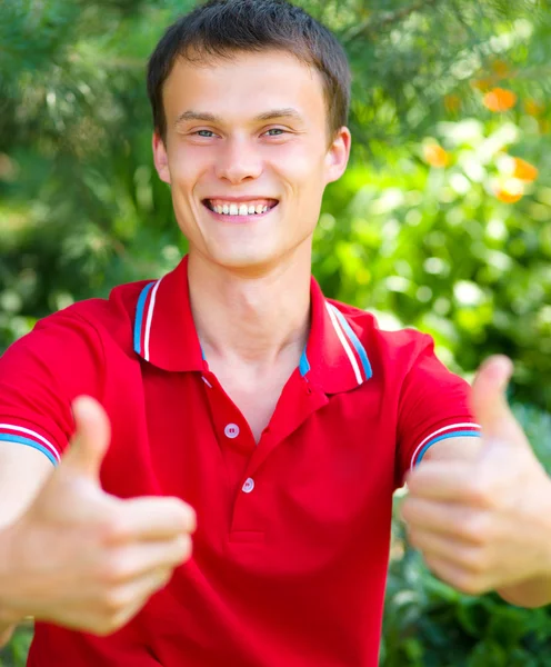 Unga glada student visar tummen upp skylt — Stockfoto