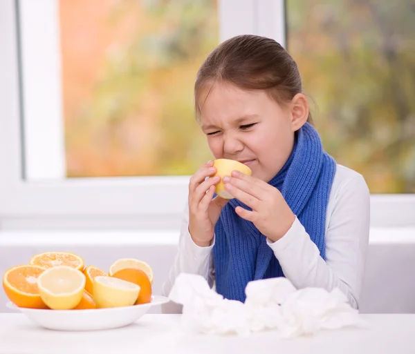 Chica trata de probar una rebanada de naranja —  Fotos de Stock