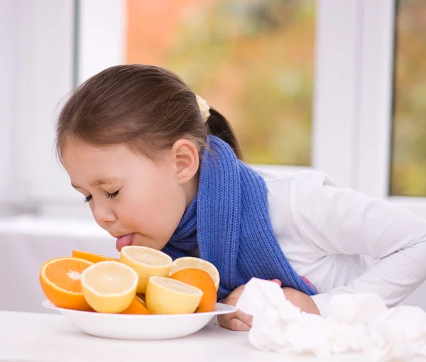 Menina tenta provar uma fatia de laranja — Fotografia de Stock