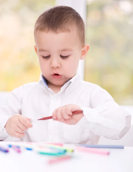 Petit garçon dessine sur du papier blanc Image En Vente