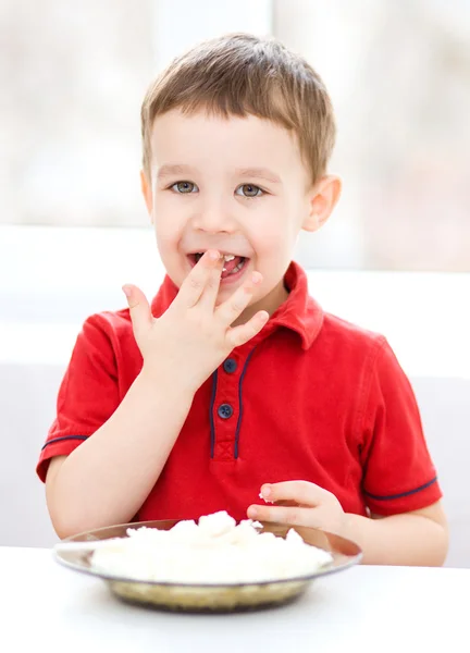 Cute little boy is eating cottage cheese — Stock Photo, Image