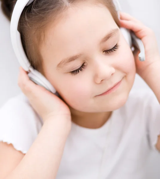 Lille pige nyder musik ved hjælp af hovedtelefoner - Stock-foto