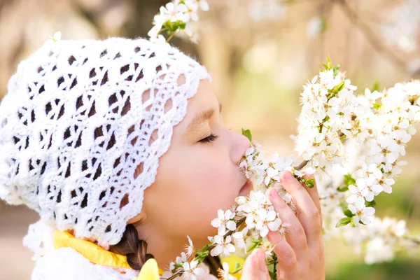 Liten flicka att lukta blommor utomhus — Stockfoto