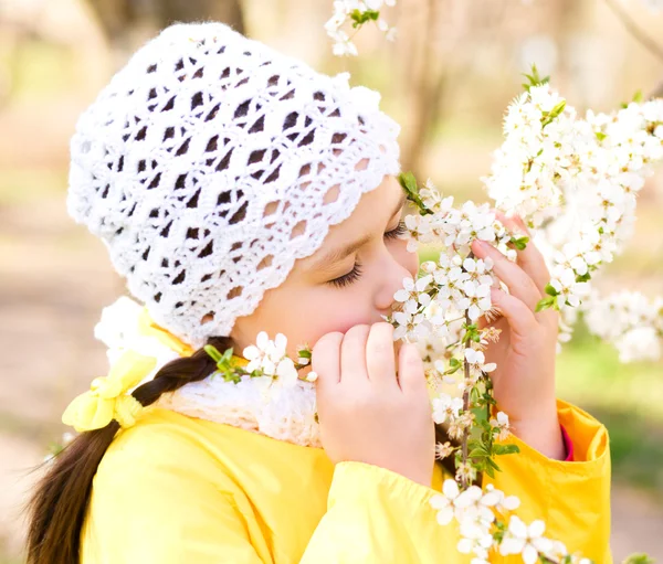 Liten flicka att lukta blommor utomhus — Stockfoto