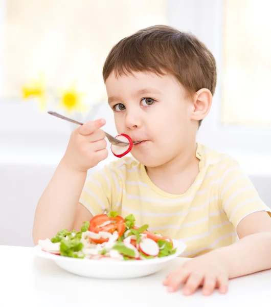 Sevimli küçük oğlan sebze salatası yiyor Telifsiz Stok Fotoğraflar