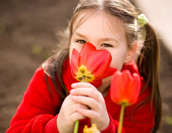Little girl smelling flowers outdoors — Stock Photo, Image