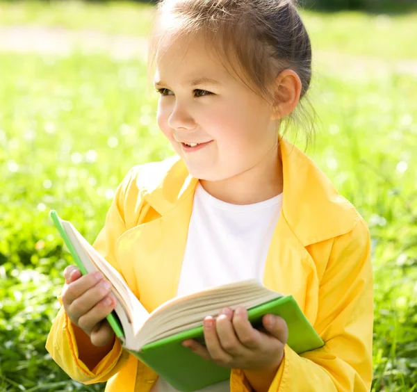Klein meisje is het lezen van een boek buitenshuis — Stockfoto